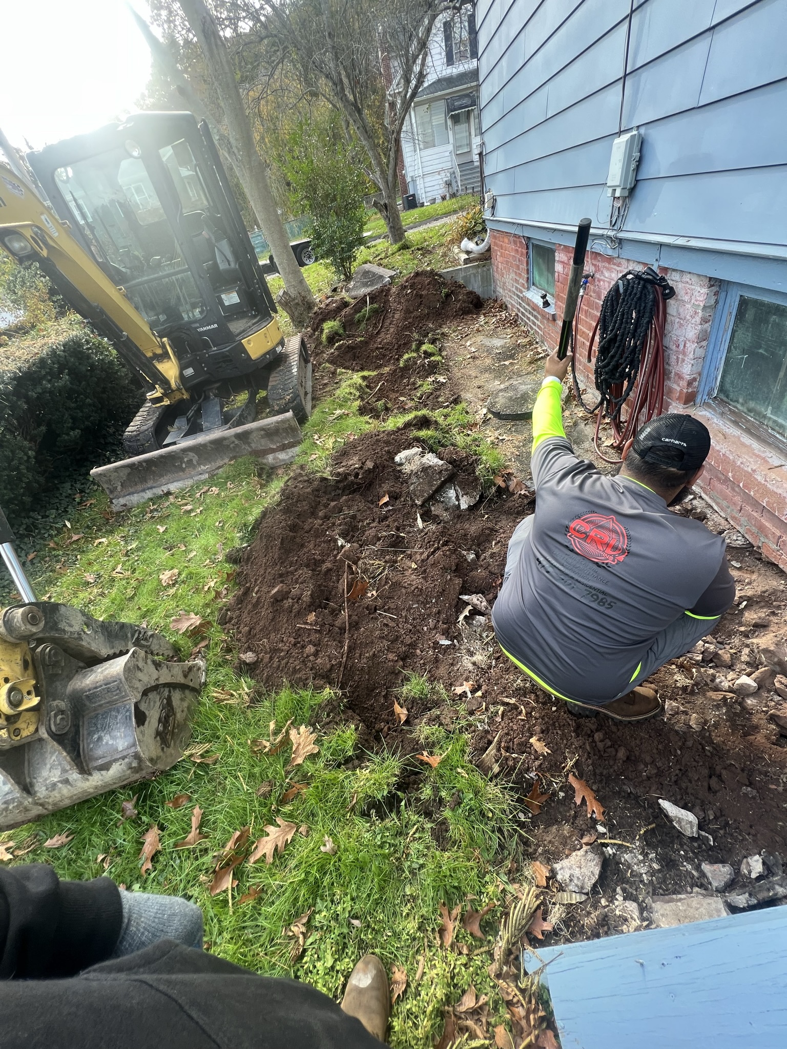 Excavated exterior foundation area with equipment and workers