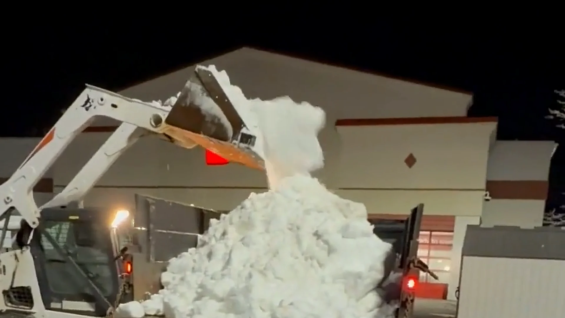 Frame from CRL snow-operations footage showing equipment relocating snow at a commercial property
