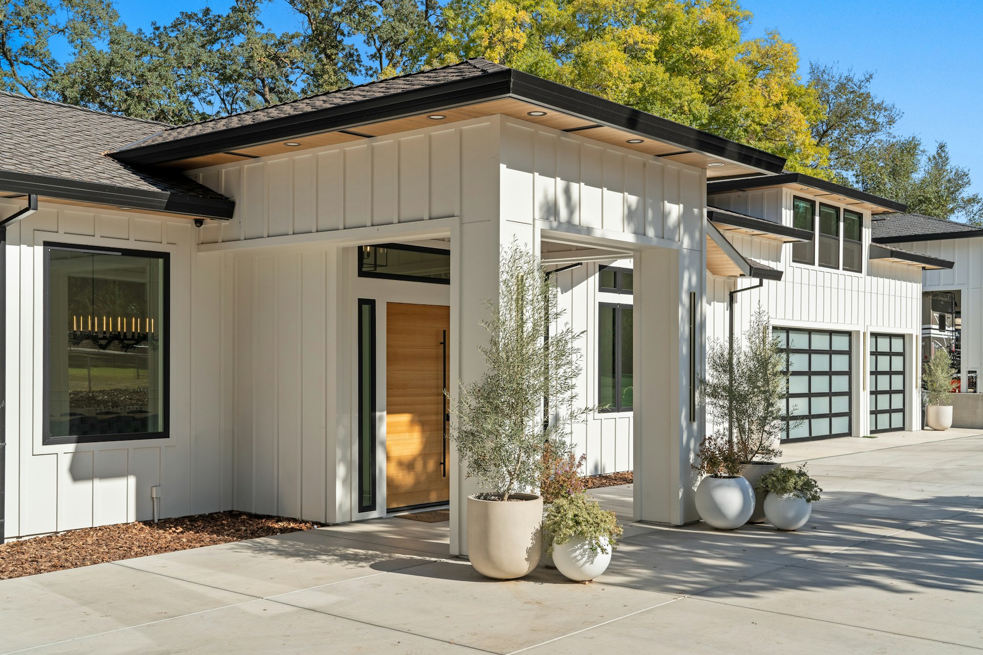 Real home exterior with white siding, dark-framed windows and a wood entry door