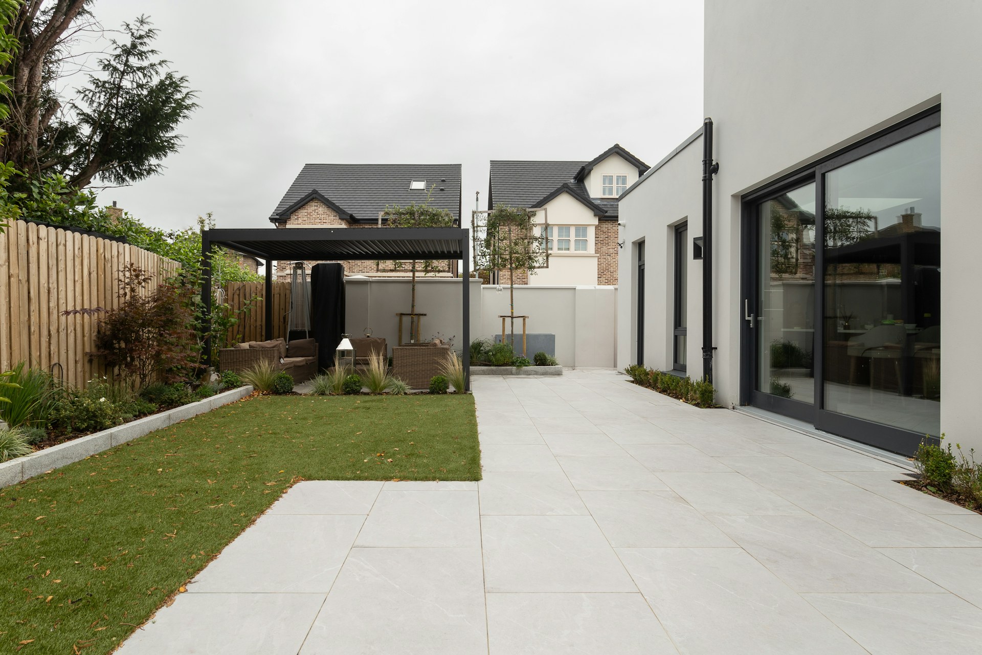 Landscaped backyard with a stone terrace and covered outdoor seating
